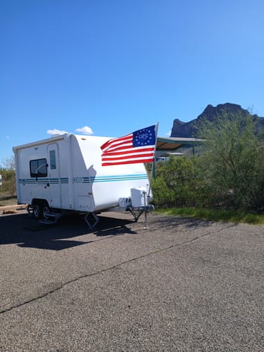 Reviewer's America 250™ stick flag mounted on the front of a white travel trailer.