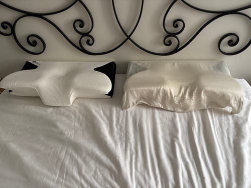 Le coussin d'alignement cervical Cellsius d'un client sur un lit, à côté d'un oreiller traditionnel.