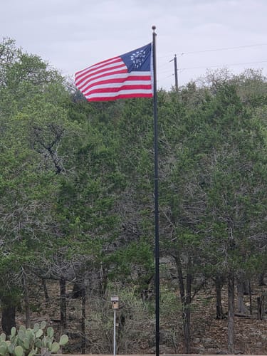 Customer's Betsy Ross Flag flying on a tall flagpole in a wooded area.