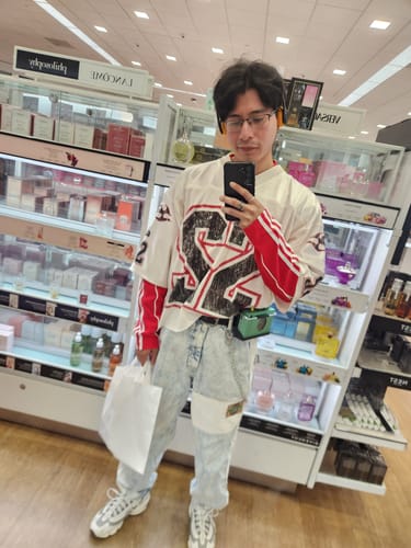 Reviewer showing the fit of the Personsoul Split Sleeve Racing T-shirt while taking a selfie in a store.