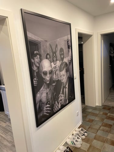 Customer's large, black-framed AREA 51 art print hanging on a white wall in a hallway.