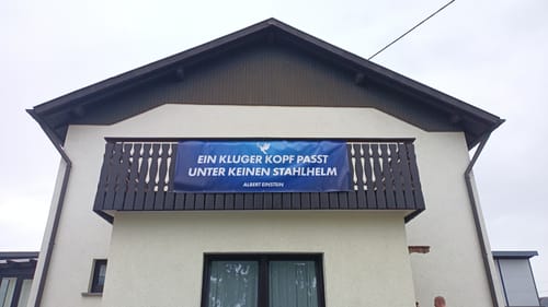 Rezensent zeigt das lange PVC-Banner, das an einem Balkongeländer hängt.