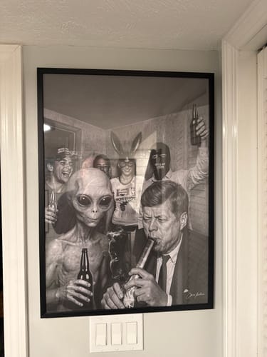 Reviewer's 'The Neighbors' art print, framed in black and hanging on a wall in their home.