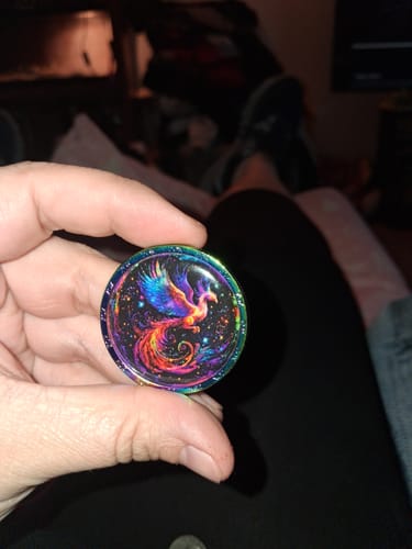 Customer holding the vibrant Amor Fati Interactive Coin, showing the colorful phoenix design.