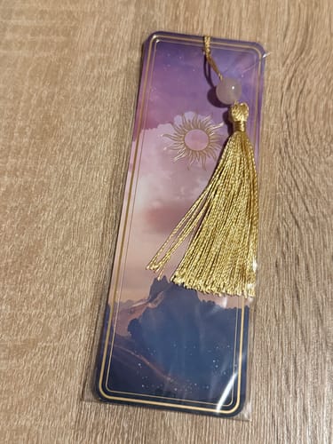 Rezensent zeigt das magische Lesezeichen mit Rosenquarz und goldener Quaste in der Verpackung.