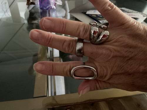 Close-up of a customer's hand wearing three bold, silver-colored rings from the WaterProof Jewelry Bundle.