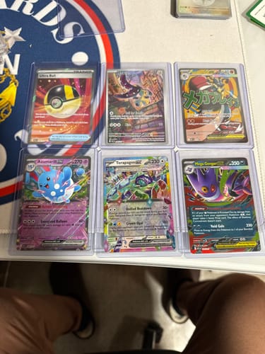 Customer showcasing six trading cards in clear top loaders from the Ultimate Card Protection Bundle.