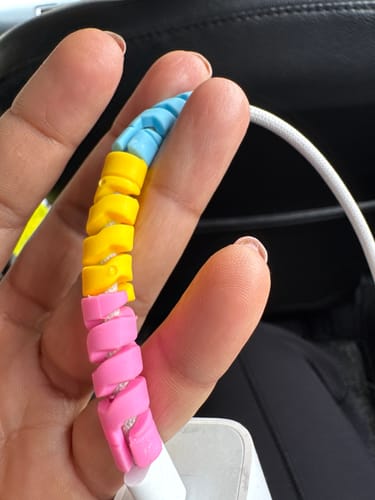 Customer holding a colorful spiral Cable Protector on a charging cord.