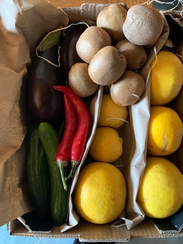 Foto eines Kunden von der Obst- & Gemüsebox „Kretas Garten“, gefüllt mit Kiwis, Zitronen, Gurken, Chilis und einer Aubergine.