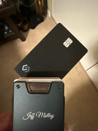 Customer holding the black SPOTMINDERS Tracking Card PRO next to a minimalist wallet.