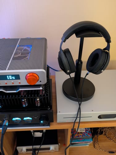 Customer's black Utopia 2022 headphones on a stand next to an audio amplifier setup.