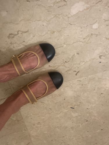 Customer wearing the beige and black Coco Beach Mary Jane Flats on a marble-style floor.