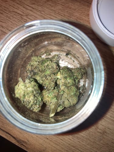 Customer's overhead view of several green Biscotti Mintz buds in an open glass jar.