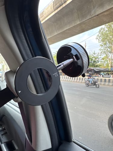 Customer's black MagPro Magnetic Phone Holder mounted inside a car next to the window.
