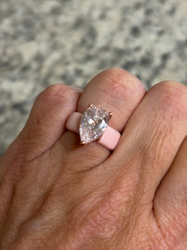 A customer's hand wearing the pink Silicone Ring with a large, pear-cut stone.