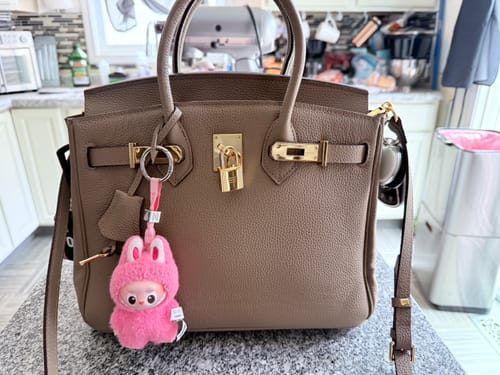 Customer's taupe LALUVA Warkin Bag with gold hardware and a pink keychain, sitting on a kitchen counter.