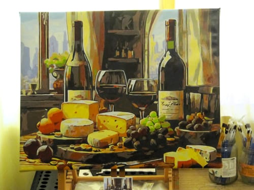 Reviewer's completed 'Wine and Cheese Delight' paint by numbers canvas displayed on a small easel.