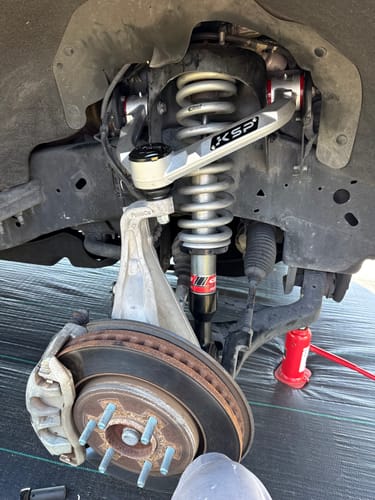 Customer's installed Aluminum Forged Upper Control Arm on a truck's front suspension with the wheel removed.