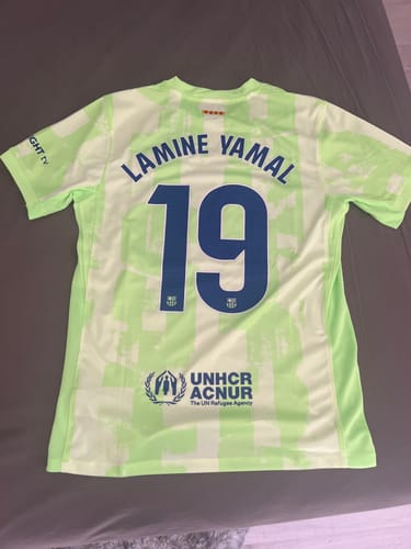 Le client montre le dos de son maillot vert Barcelone avec le flocage 'Lamine Yamal' et le numéro 19.