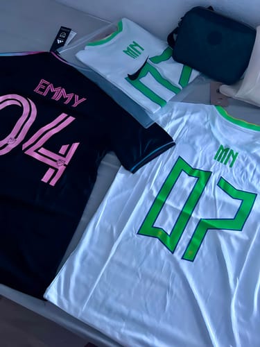 Photo d'un client montrant trois maillots de football personnalisés, un noir avec des détails roses et un blanc avec des détails verts.