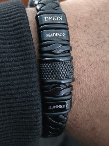 Customer's personalized black bracelet on their wrist, engraved with the names Deion, Madison, and Kennedy.