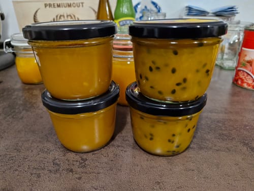 Kunde zeigt vier Gläser mit Marmelade, die aus den reifen Bio-Mangos zubereitet wurde.
