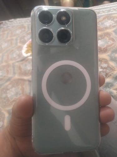 A customer holds the back of their smartphone, which is inside a clear case with a white magnetic ring.