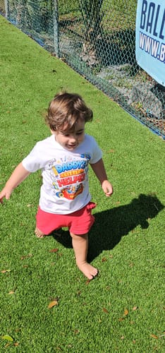 Customer's toddler wearing the white Daddy's Little Helper tee and red shorts on green grass.