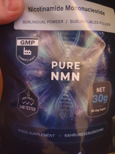 A reviewer holds the dark packaging for Nutriop PURE-NMN Nicotinamide Mononucleotide sublingual powder.
