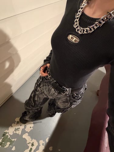 Close-up of a reviewer wearing the black flared patchwork jeans, showing the deconstructed pattern from above.