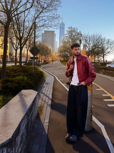 A customer wearing the red Personsoul croc-effect leather jacket on a city path.