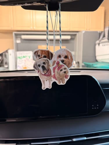 Customer's two custom air fresheners with photos of their dogs stacked and hanging from a car rearview mirror.