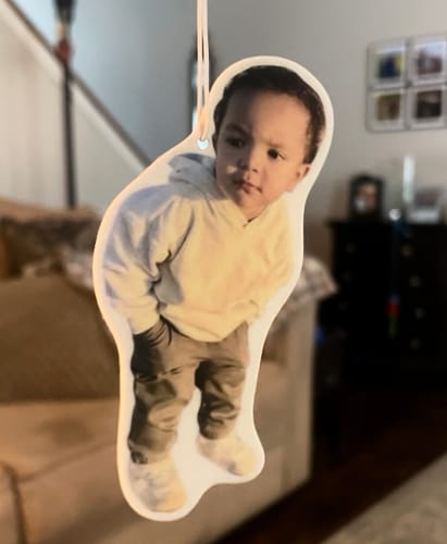 Reviewer's Custom Air Freshener hanging indoors, featuring a sharp, custom-cut photo of a young child.
