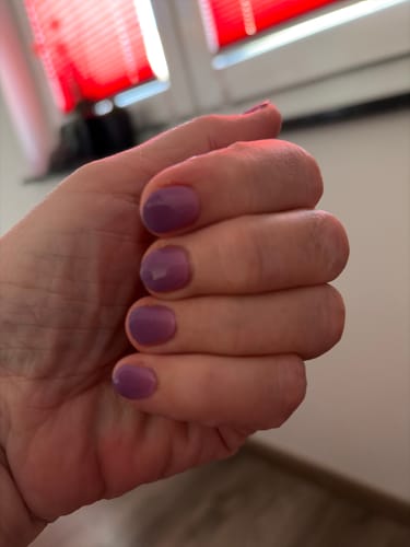 Nahaufnahme der Hand einer Kundin, die die lila UV-Gel-Nagelfolien 'Dancing Till Dawn' auf kurzen Nägeln trägt.