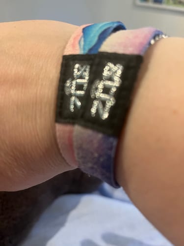 Close-up of a customer wearing two colorful Be Still And Know bracelets stacked on their wrist.