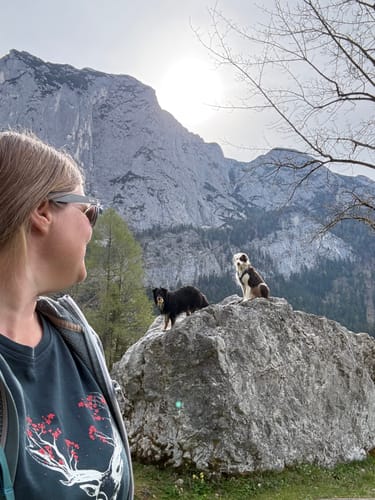 Eine Kundin trägt das dunkle Hirsch Blüten Bio Damen Shirt bei einer Wanderung vor einer Bergkulisse.