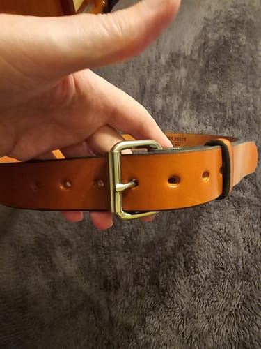 Close-up of a customer holding their brown leather The Gunner belt, showing the sturdy buckle.