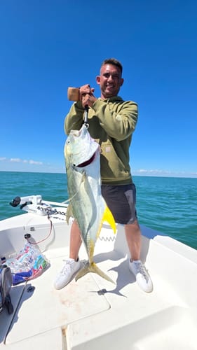 Customer on a boat holding a large, gold-tailed fish caught using the Kden 365 Shad Lure.