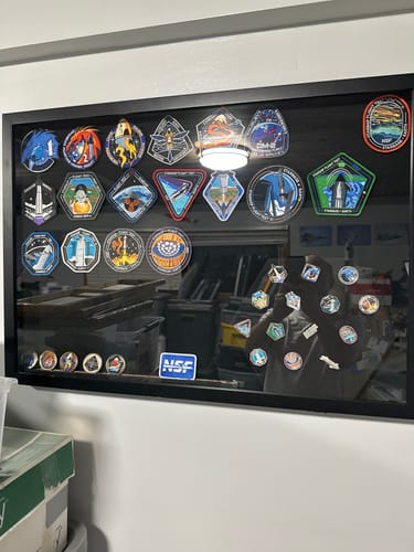 Customer's Starship Flight Pins displayed in a large black shadow box as part of a bigger patch collection.