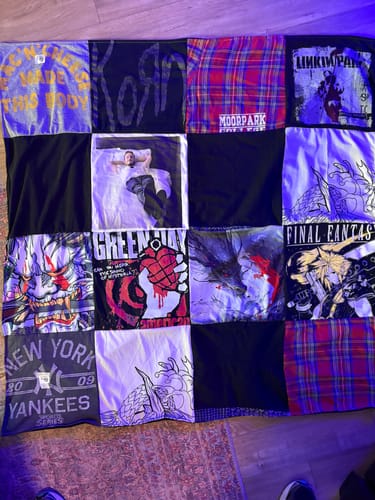Customer's custom T-Shirt Quilt spread on the floor, showing patches from band shirts, plaid, and a photo.