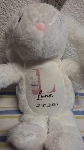 Rezensent zeigt den niedlichen, weißen Plüschhasen, der mit dem Namen Luna und einem Datum auf dem Bauch personalisiert ist.