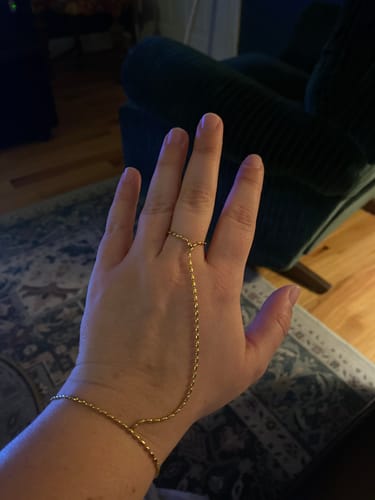 Reviewer's hand wearing the delicate gold Zahara Handchain, showing the fit from wrist to finger.