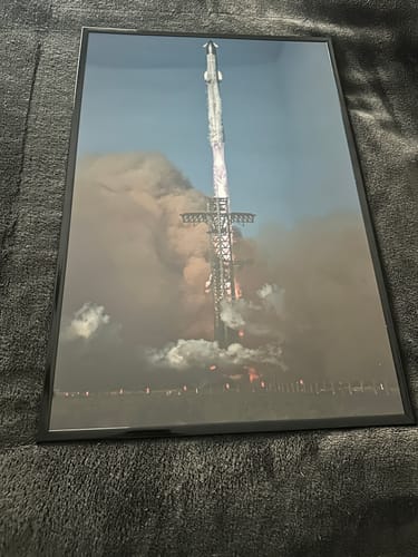 Customer's 'Flying High Again' premium print of a rocket launch, displayed in a sleek black frame.