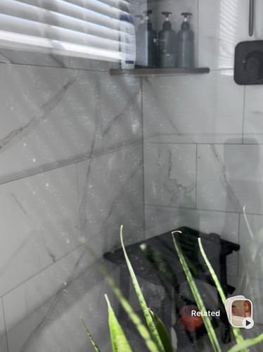 Close-up of a reviewer's clean shower glass door after using the Bathroom Concentrate.