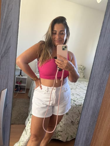 Avaliadora tira uma selfie no espelho, mostrando sua case Nora rosa com alça pendurada.