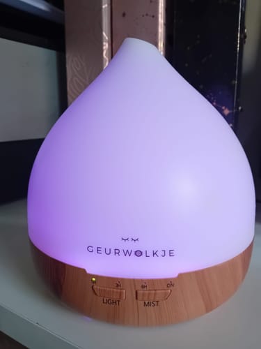 Klant's Geurwolkje diffuser met lichte houten basis, verlicht met een zachte paarse gloed.