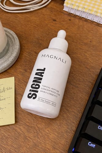 Customer's white bottle of Magnali Signal serum sitting on a wooden desk.