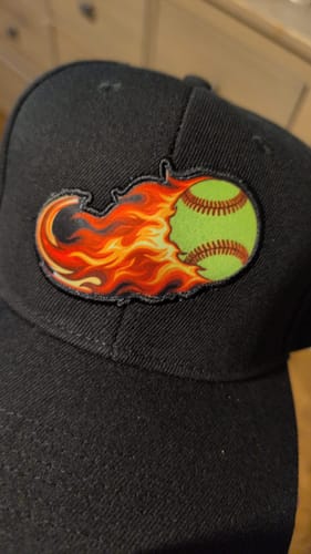 Reviewer's close-up of a custom patch on a black cap, showing a baseball on fire.