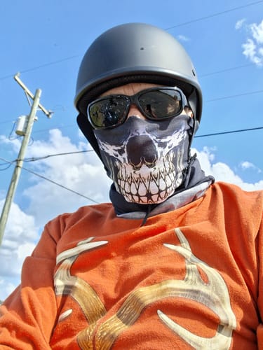 Customer takes a low-angle photo wearing the Reaper Grin Skull Neck Gaiter with a helmet and sunglasses.