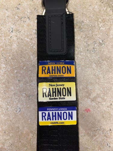Customer's three custom license plate enamel pins for New York, New Jersey, and Pennsylvania on a black strap.